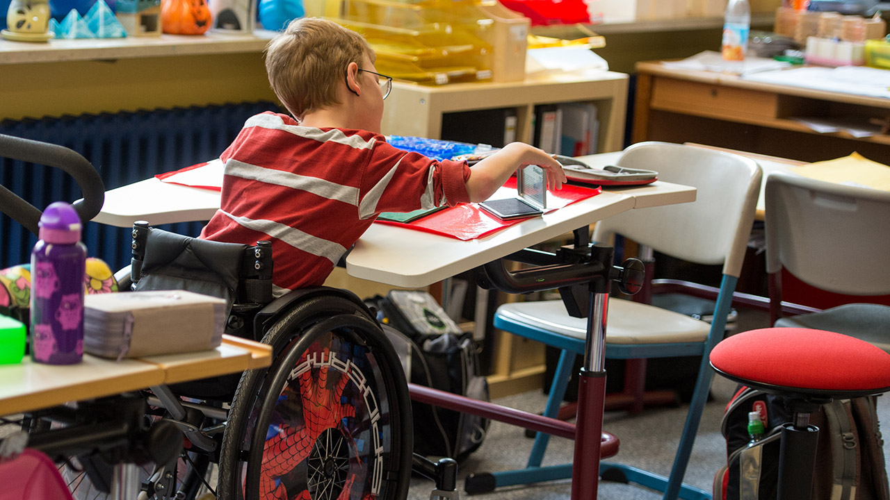 Schulkind im Rollstuhl nimmt am Unterricht teil.