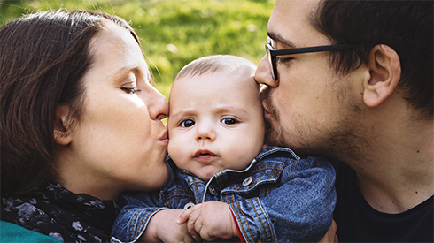 Mutter und Vater küssen ihr Baby Mutter und Vater küssen ihr Baby