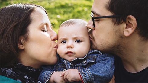 Mutter und Vater küssen ihr Baby