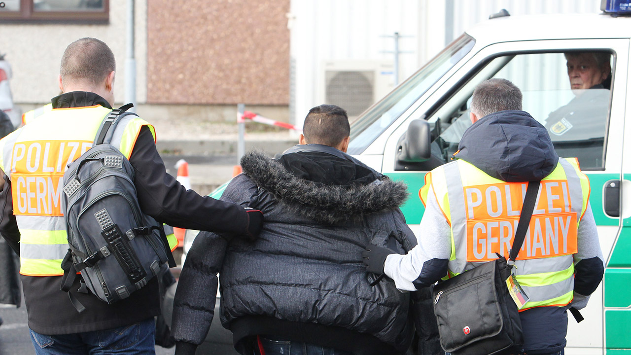 Polizisten begleiten einen straffällig gewordenen Asylbewerber