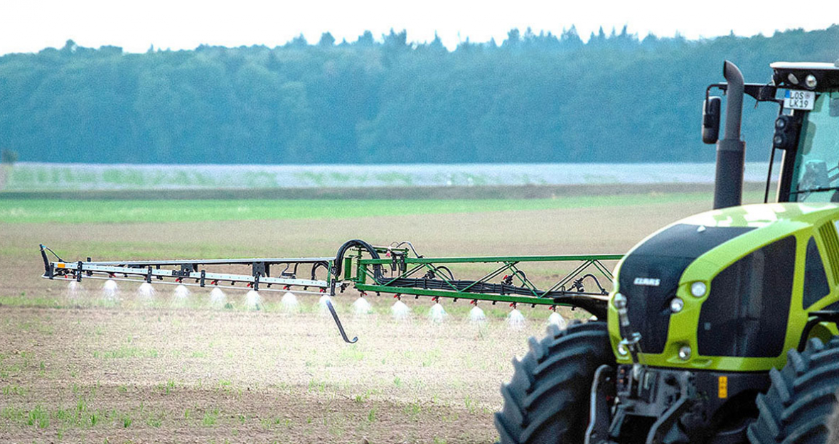 Traktor fährt mit Pestizidspritze auf einem Feld