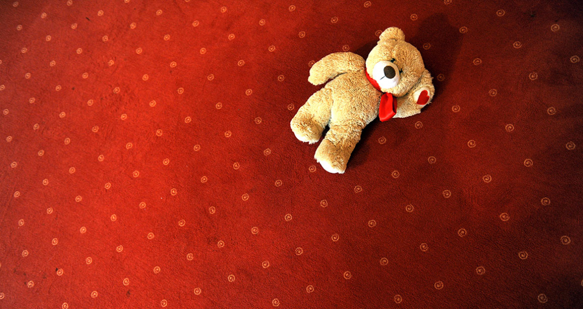 Teddybär liegt auf rotem Teppich