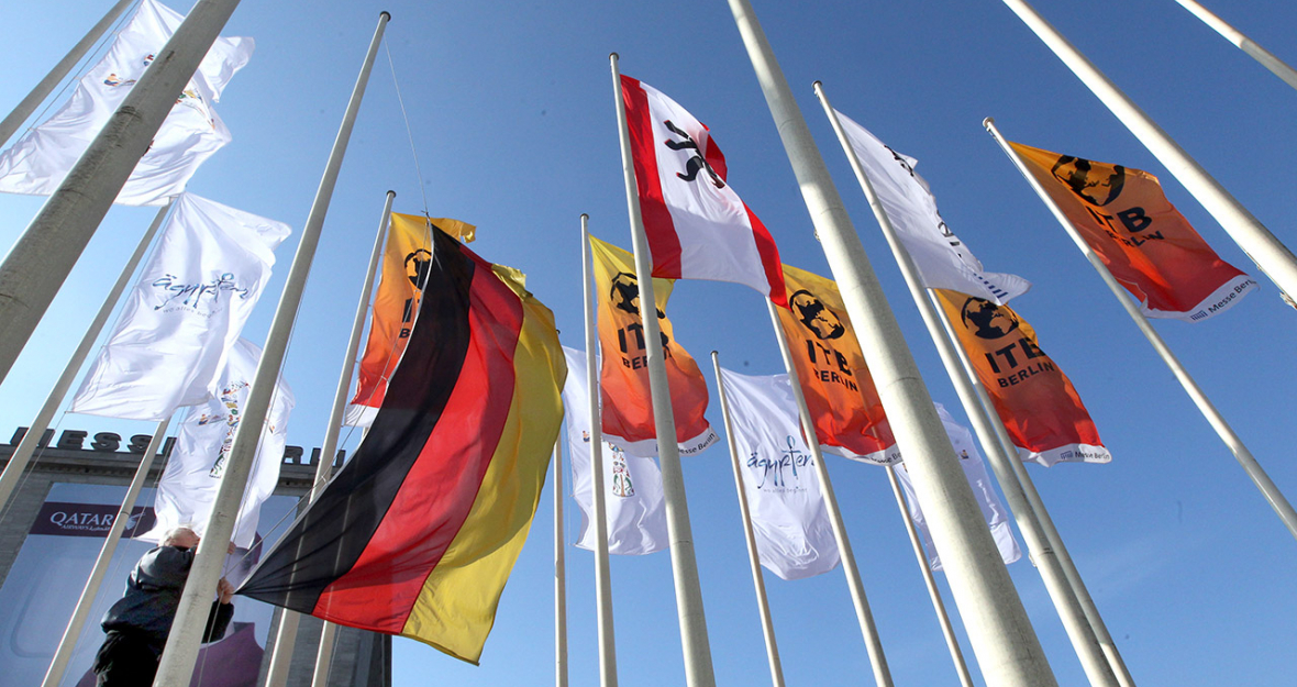 Ein Mitarbeiter der Messe Berlin zieht vor dem Hauptgebäude der Messehallen in Berlin Flaggen der Ausstellerländer hoch.