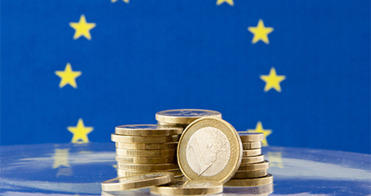 1-Euro-Münzen vor der europäischen Fahne_490x275