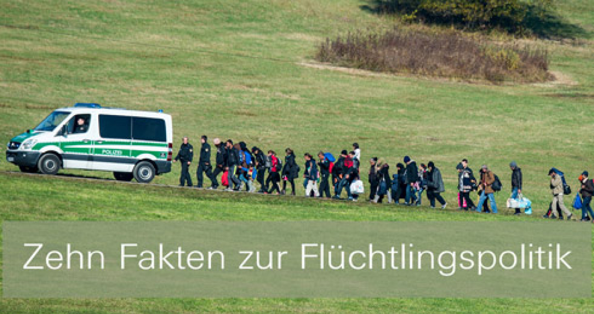 Flüchtlinge hinter einem Polizeiauto auf dem Weg zu ihrer Unterkunft.