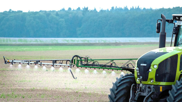 Traktor fährt mit Pestizidspritze auf einem Feld