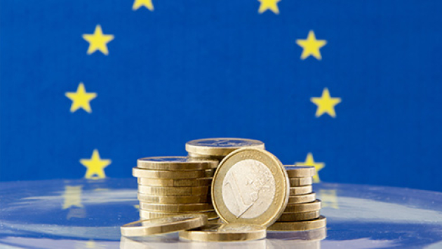 1-Euro-Münzen vor der europäischen Fahne_490x275