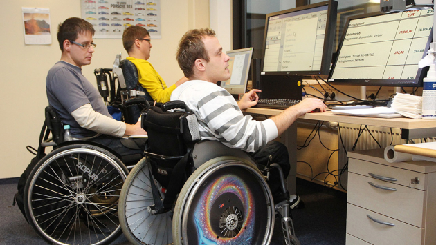 Mitarbeiter einer Behindertenwerkstatt arbeiten am PC
