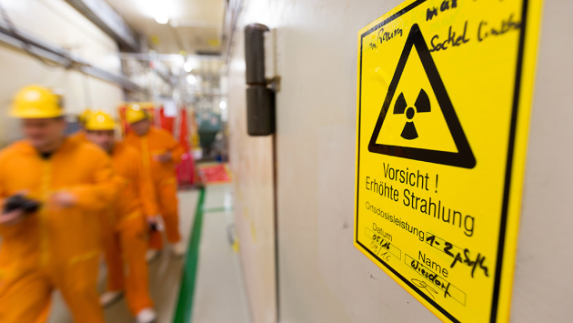 Mitarbeiter gehen an einem Schild mit der Aufschrift 'Vorsicht! Erhöhte Strahlung' vorbei Mitarbeiter gehen an einem Schild mit der Aufschrift 'Vorsicht! Erhöhte Strahlung' vorbei