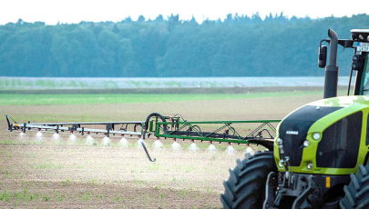 Traktor fährt mit Pestizidspritze auf einem Feld
